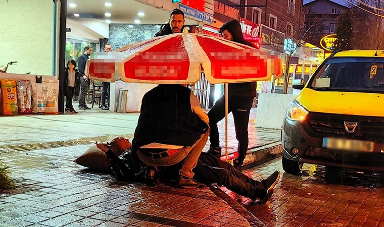 Otomobilin çarptığı yayayı yağmurdan korumak için şemsiye tuttu